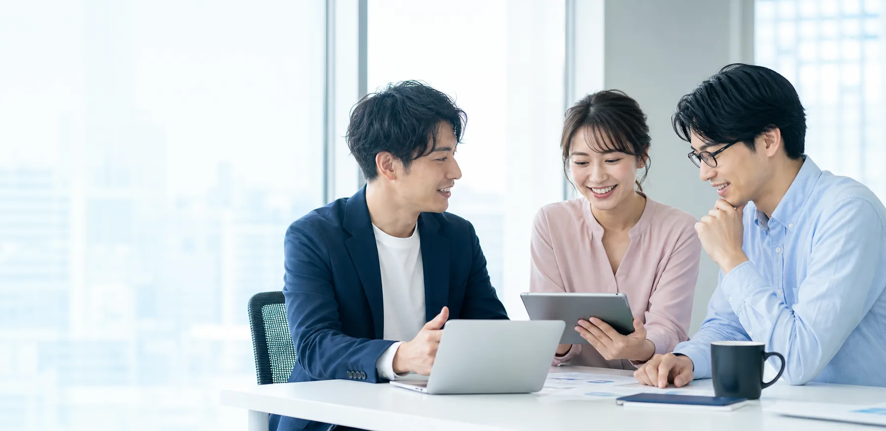 オフィスでタブレットを囲み協力する3人